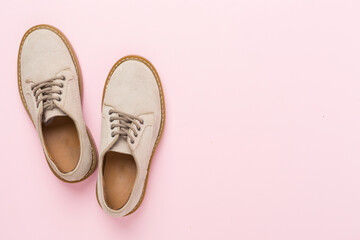 Beige suede shoes on color background, top view