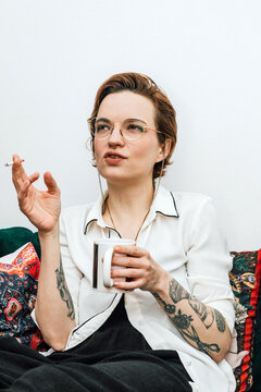 Tattooed Woman Enjoying a Coffee and Cigarette