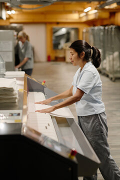 Woman Using Mangle At Work In Laudry