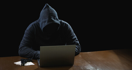 Portrait hacker spy man one person in black hoodie sitting on table looking computer laptop used login password attack security to data digital internet network system night dark background copy space