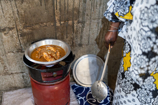 Woman cooking traditional senegalese food on a gas stove