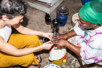 Volunteer helping local woman peeling eggs in kitchen in senegal