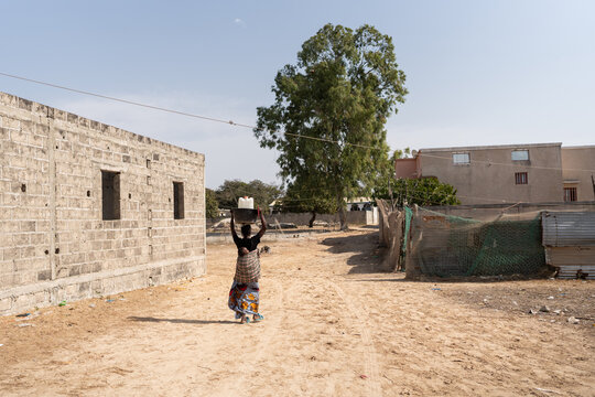 African mother carrying water on head walking on dirt road