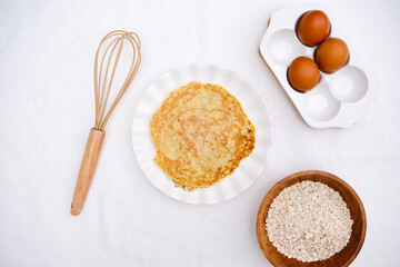  Pancake and ingredients: eggs, spatula, oatmeal, for healthy breakfast on white background top view.