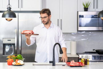 Hispanic 40s man in chef uniform hold meat beef at kitchen. Cooking meat. Restaurant menu with meat. Cooking, advertising meat concept. Raw beef steak.