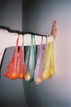 Arm holding multiple colored plastic bags
