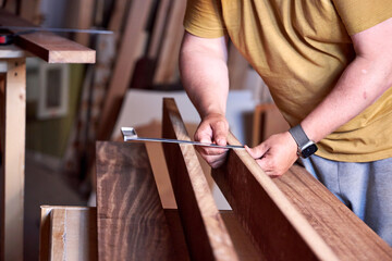 a man in a home carpentry workshop measuring boards close-up of hands