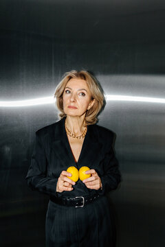 Thoughtful businesswoman holding lemons
