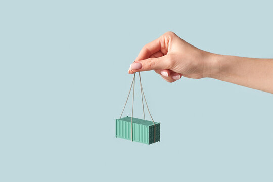 Hand of woman holding rope with attached green container