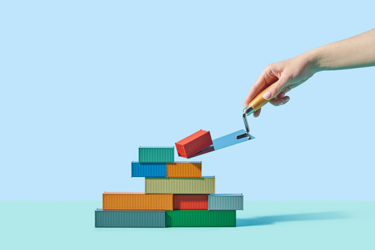 Caucasian person placing red metal container in stack with trowel