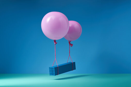 Blue metal box floating in air while being attached to gel balloons
