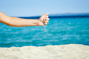 A hands pouring sand near the seashore on weekend nature travel