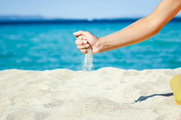 A hands pouring sand near the seashore on weekend nature travel