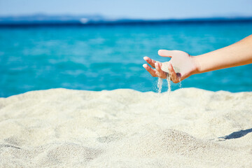 A hands pouring sand near the seashore on weekend nature travel