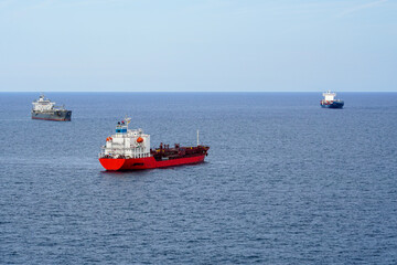 Shipping at sea, three different ships moving in three different directions, blue sky above horizon