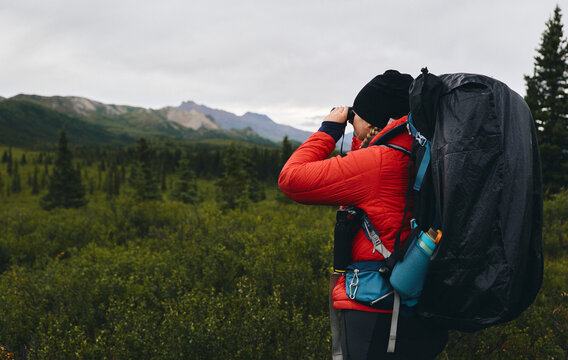 Female hiker observing with binoculars 
