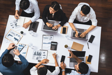 Top view analyst team utilizing BI Fintech to analyze financial data at table in meeting room. Analytic BI dashboard power on paper for business insight and strategic marketing planning. Prudent