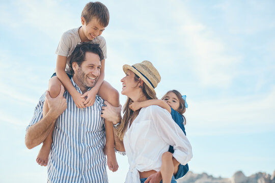 Family, happy and carrying on beach for travel, holiday and bonding together in summer with sunshine. Mom, dad and kids by ocean for relax, vacation and relationship with shoulder ride and blue sky