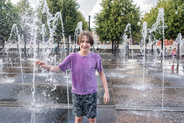 smiling 11 year old boy near dry fountain in park in summer