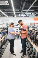 Indian Couple choosing vacuum cleaner, electronics store