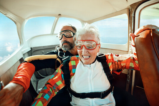 Elderly woman preparing for tandem skydive with instructor in airplane