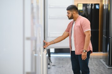 Smart modern indian male customer choosing large fridges in domestic appliances section