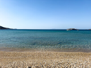 Beach in Greece. Clear sea water and wet small pebbles. Summer holiday