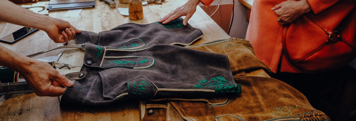 A master tailor shows an embroidered pattern on leather.
