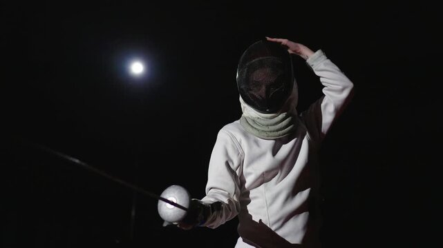 Motivated Junior Female Sportsperson In Fencing Uniform Putting Fencing Mask On Head Before Training