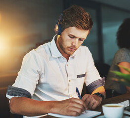 Man, headphones and writing at night in office for creative notes, planning and listening to music...