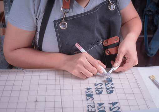 Young woman removes excess material with weeding tool, cutting plotter workplace.