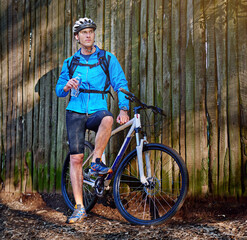 Nature, rest and man by bicycle with bottle for hydration, recovery or thirsty after workout in...