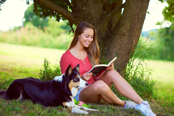 Woman, reading book and dog to relax in park, countryside vacation and novel for learning fiction. Female person, story and animal support for love in nature grass, bonding and pet for literature