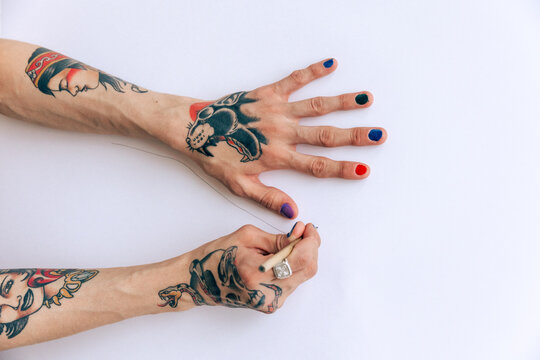 Tattooed Hands Sketching Art on White Paper