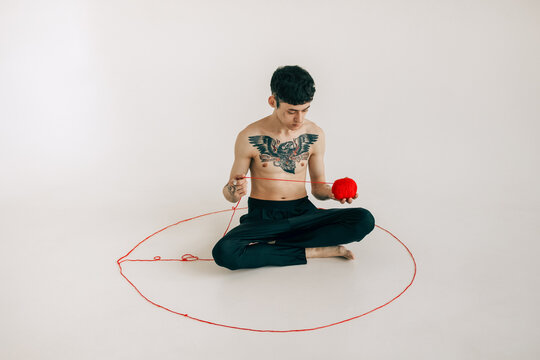 The man with the tattoos is sitting 