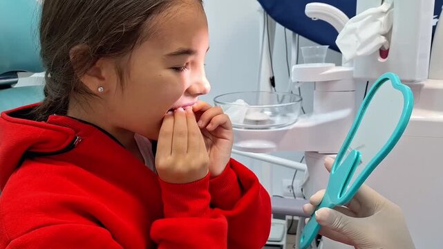 A girl is sitting , learning to put on a removable orthodontic device for bite correction