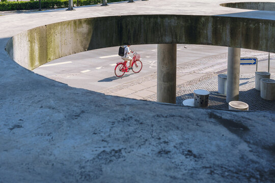 A cyclist on a red bicycle rides through an urban area 