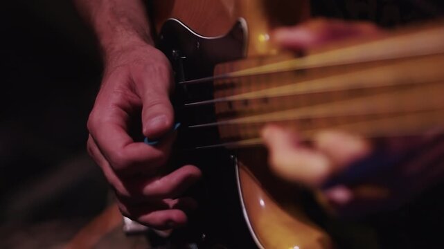 Guitar player close up playing on an electric guitar in low light during the performance in the studio. Guitarist delicately performing a song