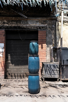 Stacked blue barrels in front of old building