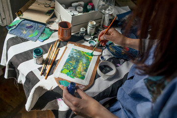 hands of an artist who paints a picture