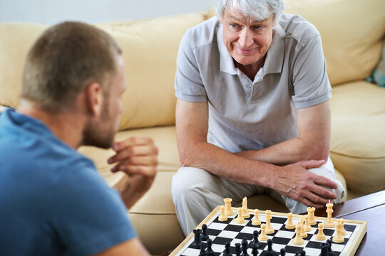 Senior dad, man or chess checkmate in home for games or challenge with strategy or problem solving. Happy mature parent, smile or board for playing or learning thinking skills for cognitive function