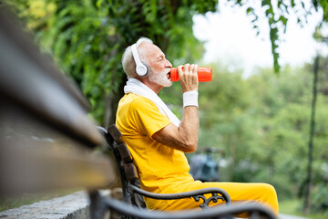 Senior sportsman taking a break after long run and drinking water.