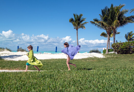 Kids on vacation run around resort with beach towels