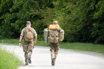 2 British male soldiers tabbing with heavy bergens