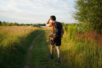 Young sporty man walking through fiels with a backpack in bavaria.