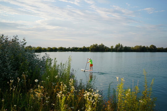 Mann auf einem Standup-Padde (SUP) am Kronthaler Weiher bei Erding, Bayern.