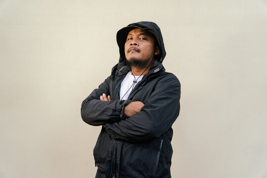 Portrait of Asian man wearing adventure clothes and doing various poses. Macho and smiling adult man wearing white shirt and jacket with hood isolated on beige background