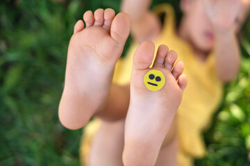 Naklejka premium A sad little smile face on a child's foot. Dermatological diseases of the feet and nails, fungal infection that causes pain, itching and discomfort