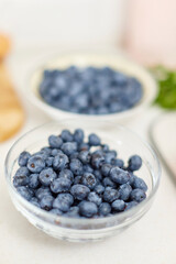 Fresh blueberries in glass bowl on white table. Healthy eating