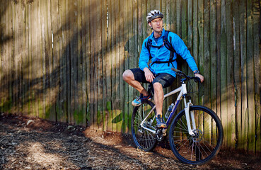 Naklejka premium Man, bike and break from cycling adventure in outdoor, thinking and plan for extreme sports. Male person, athlete relax and training in nature for triathlon, forest and riding exercise for reflection